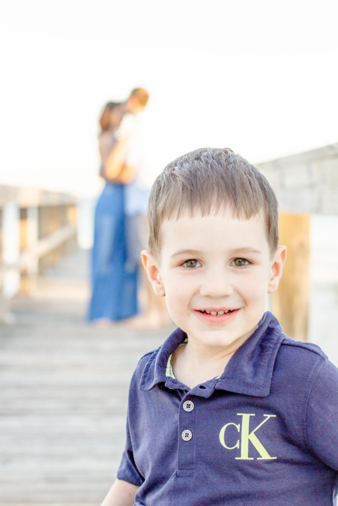A little boy on the boardwalk in Pensacola FL during a family beach photo session with Jenny Macy Photography