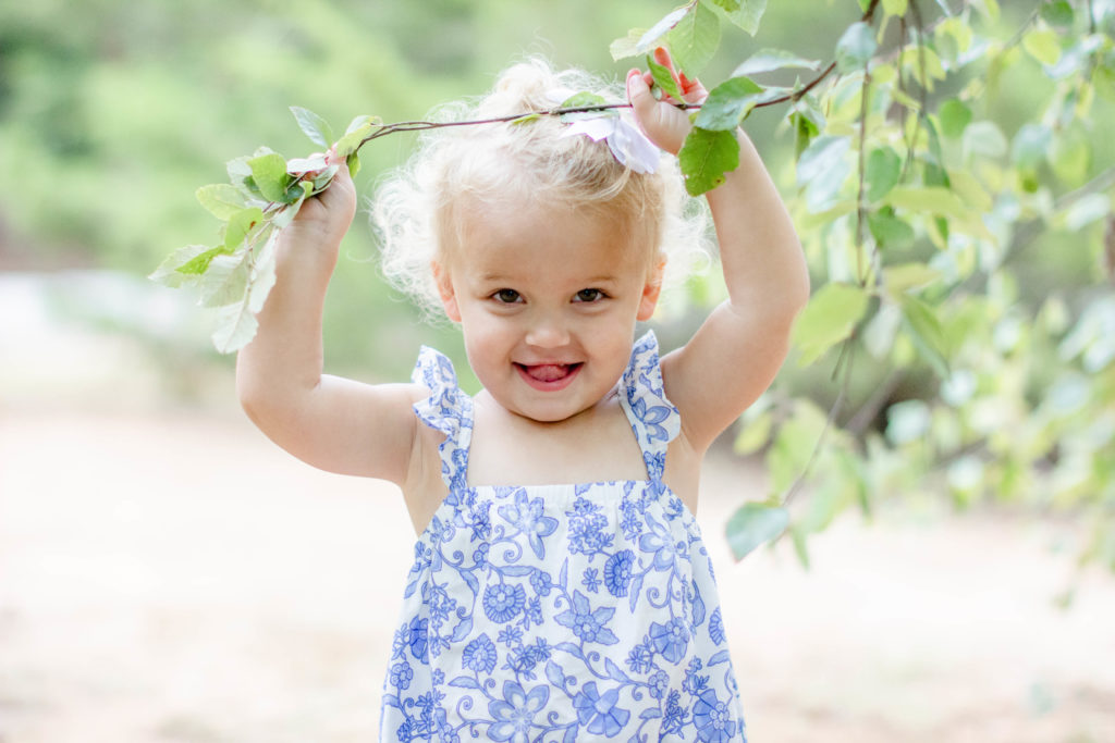 A little girl with a tree branch in a park in Greenville SC during a family and maternity session by Jenny Macy Photography.