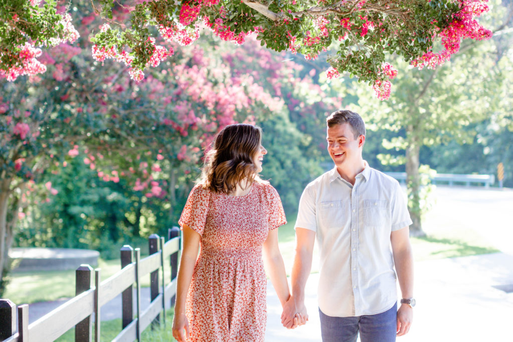 A couple walking down a street of flowers with a fence during a Greenville SC Family Mini Session Maternity Session by Greenville family photographer Jenny Macy Photography