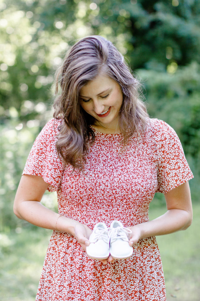 A woman holding baby shoes during a Greenville SC Family Mini Session Maternity Session by Greenville family photographer Jenny Macy Photography