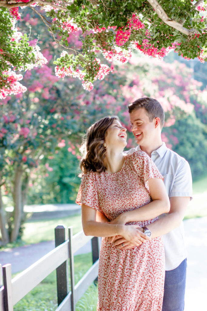 A couple laughing amongst the floral scenery in Falls Park during a Greenville SC Family Mini Session Maternity Session by Greenville family photographer Jenny Macy Photography