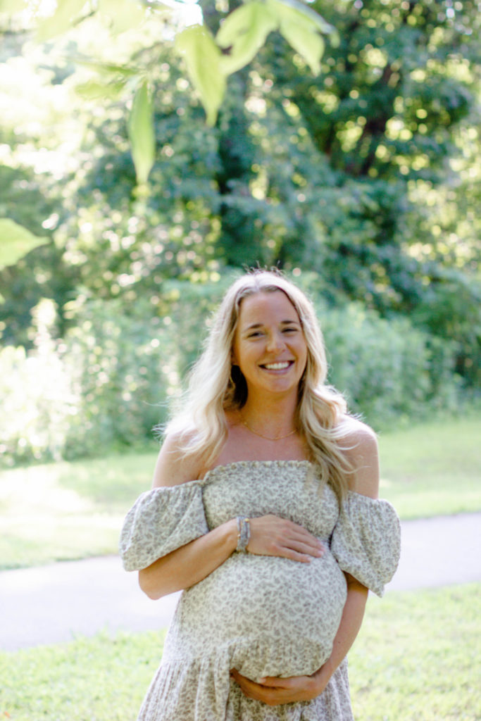 A mom laughing and walking during a maternity mini session in Greenville, SC by Jenny Macy Photography.