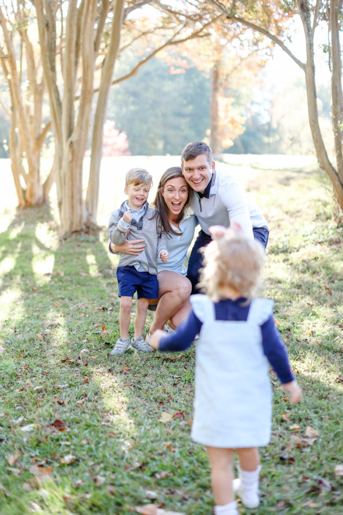 Little girl running up to her family during a fall family photo session in Greenville, SC with Jenny Macy Photography.