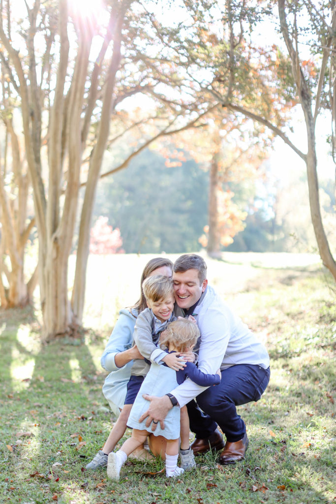 Little girl running up to hug her family during a fall family photo session in Greenville, SC with Jenny Macy Photography.