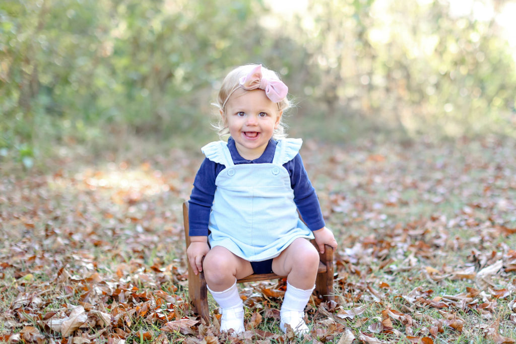 Little girl sitting among leaves during a fall family photo session in Greenville, SC with Jenny Macy Photography.