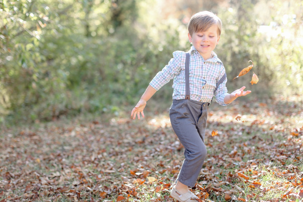 A little boy tossing leaves during a fall mini session in Greenville, SC with Jenny Macy Photography.