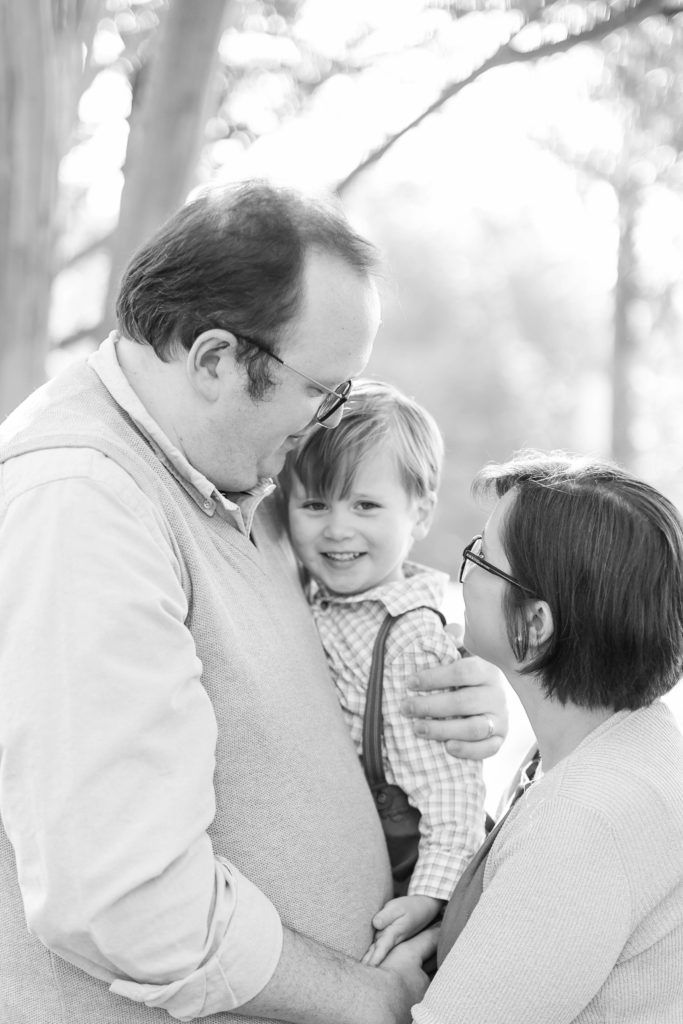 A black and white photo of a little boy and his mom and dad during a fall mini session in Greenville, SC with Jenny Macy Photography.